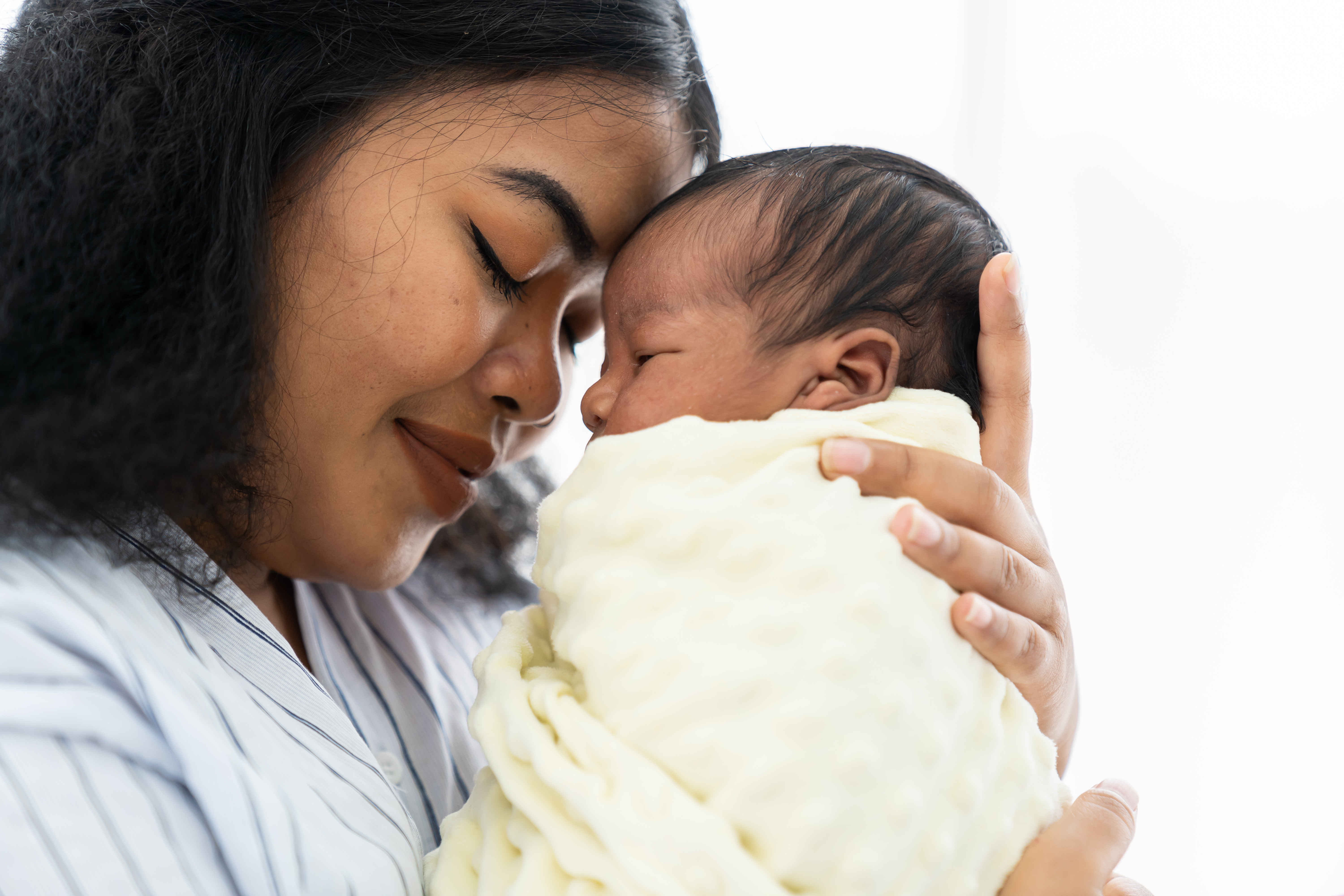Mother resting forehead on newborn baby