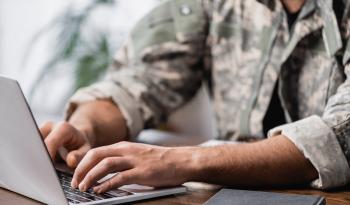 Cropped view of military man using laptop on desk