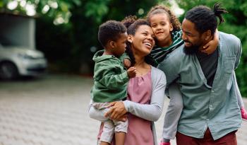 Mixed Race Family of 4, Mom, Dad, Child and Teenager smiling walking