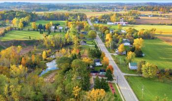 Rural town with one road, few houses, changing leaf colors outside